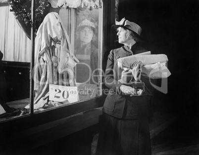 Young woman looking at a window display while reaching into her handbag