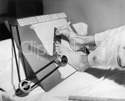 Feet of a disabled man using a drafting board