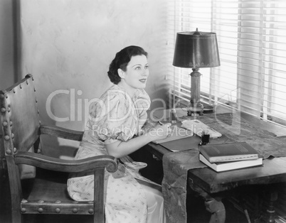 Young woman sitting at her desk writing a letter