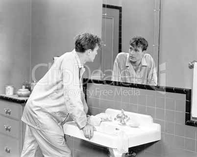 Man in bathroom looking into mirror