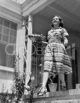 Young woman walking down steps of her terrace with a plate in her hands