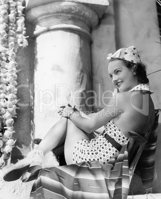 Young woman in a sun suit sitting on a chair