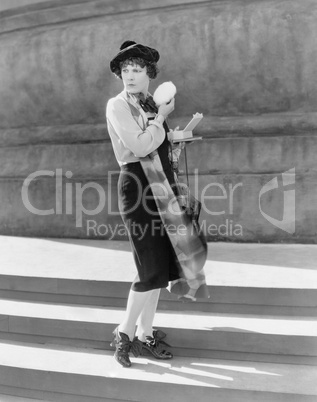 Young woman on steps, holding a powder puff