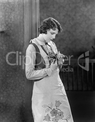 Young woman in an apron holding herbs