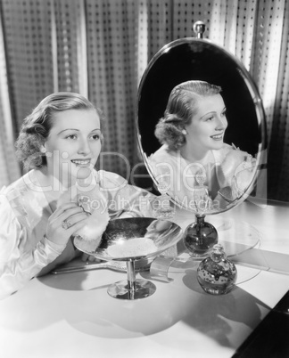 Young woman sitting next to mirror and holding a powder puff