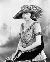 An elegant young woman with a big hat and a beautiful ornate dress