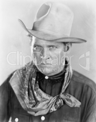 Cowboy with a hat looking sternly at the camera