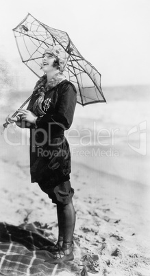 Young woman on the beach with an umbrella looking like a spider web