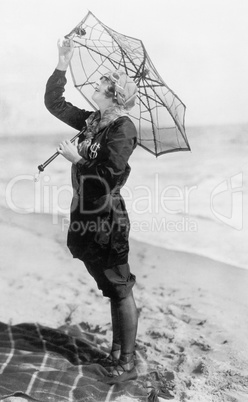 Young woman on the beach with an umbrella looking like a spider web