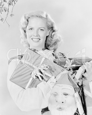 Young woman holding an arm full of presents and a Santa Claus mask