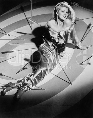 Young woman sitting on a target with arrows around her