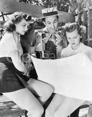 Two young women and a man looking at architectural plans