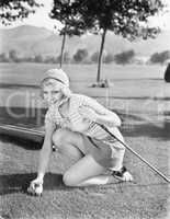 Young woman on a golf course placing a golf ball