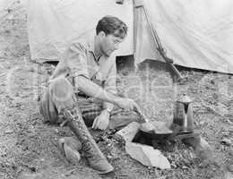 Man sitting in front of his tent preparing food