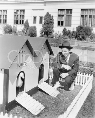 Man crouching next to duck house