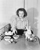 Young woman in her kitchen coloring Easter eggs