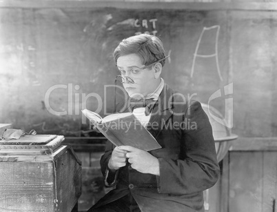 Teacher holding a book in front of a black board