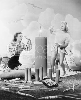 Two women sitting around fire works