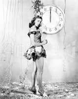 Young woman standing in front of a clock, celebrating New Years Eve