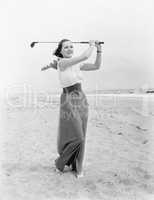 Young woman playing golf at the beach