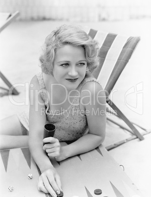 Young woman sitting at the beach playing backgammon