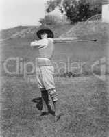 Young woman swinging a golf club on a golf course