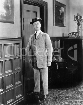 Man with hat looking silly walking into a room