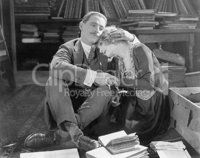 Couple sitting on the floor of a library holding each other