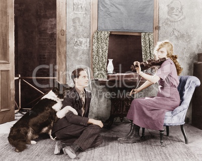 Woman playing the violin for her boyfriend and dog