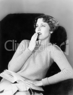 Young woman sitting on a armchair with a book