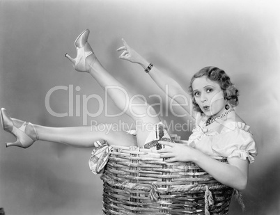 Young woman sitting in a basket looking surprised