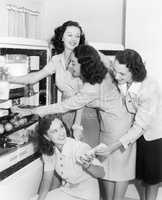 Four women taking things from a refrigerator