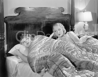 Two women together in bed under a blanket