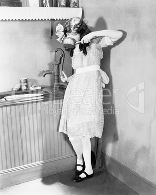 Young girl gets a sip of pump water in the kitchen