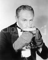 Man drinking a big glass of cold beer with mittens