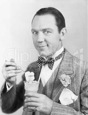 Man eating an ice-cream out of a glass with a straw
