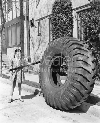 Girl playing with a huge tire and stick