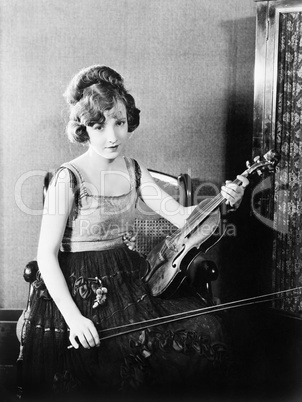 Young woman sitting on a chair and holding her violin