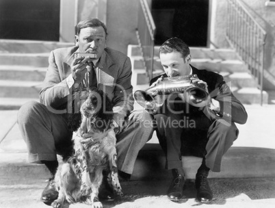 Two men playing two harmonicas with an English Setter