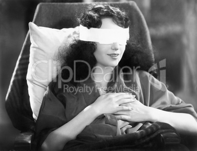 Young woman sitting in a chair with bandages over her eyes