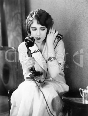 Young woman sitting on a chair holding a telephone
