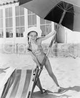 Girl placing a large umbrella into the sand