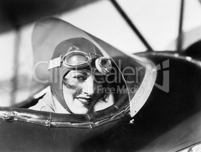 Young woman sitting in a biplane with hat and gargles