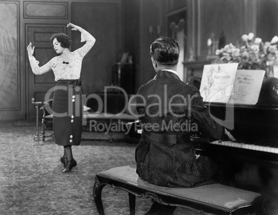 Woman dancing while her husband is playing the piano