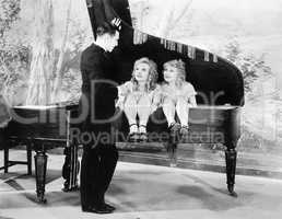 Funny image of twins sitting inside of a piano talking to a young man