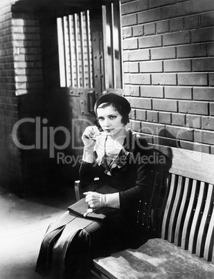 Young woman sitting n a bench in front of a jail cell