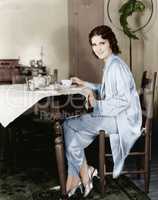 Young woman sitting at a table having breakfast tea