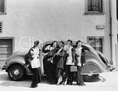 Five women standing in front of a car
