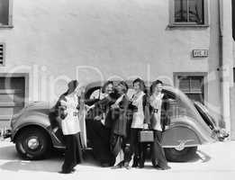 Five women standing in front of a car