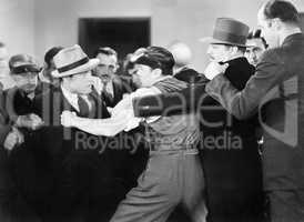 Men wrestling a man back who is trying to punch another man